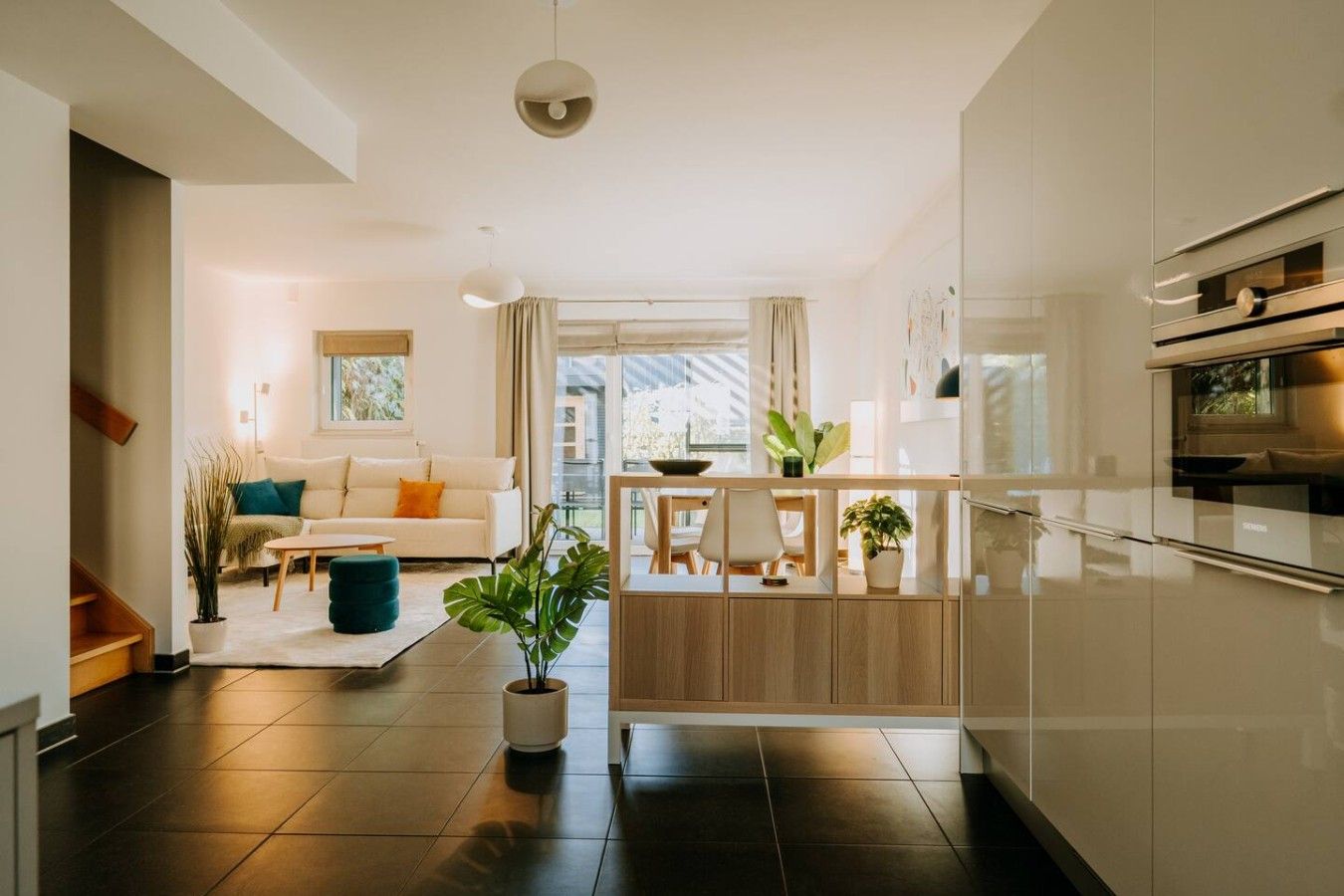 Une cuisine moderne dotée d’un îlot central, un coin repas avec un canapé et une table basse, et un escalier menant à un niveau supérieur.