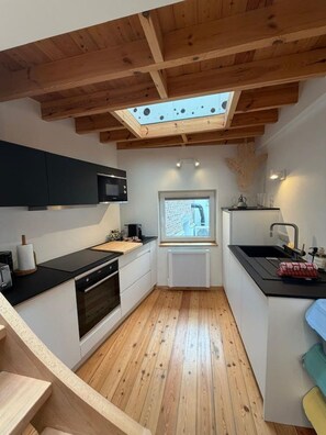 Una cucina moderna con travi in legno, un lucernario e vista sulla città.