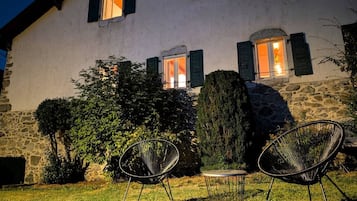 A stone building with a well-maintained lawn, two outdoor chairs, and a table.