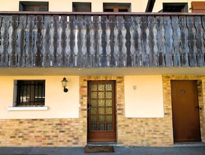 A building with a brick facade, a wooden door with a glass panel, and a small window with a metal grill. - Authentic Lake Geneva farmhouse near Évian (Larringes)