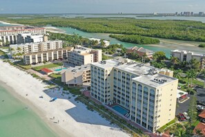 A beachfront hotel with multiple buildings, a swimming pool, and a beach area. - Direct Beach Front -- Sun, Sand, Luxury and Fun (Bonita Springs)