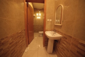 Ein schmales Badezimmer mit einem weißen Waschbecken, einer Toilette und einem Spiegel an der Wand.