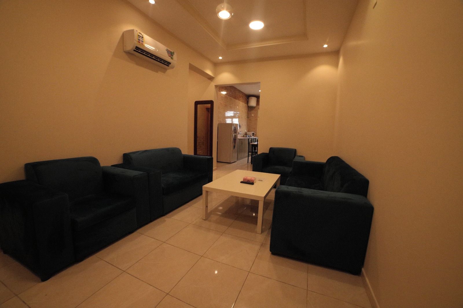 A compact living space with a kitchenette, two sofas, a coffee table, and a tiled floor.