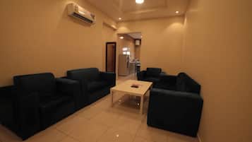 A compact living space with a kitchenette, two sofas, a coffee table, and a tiled floor.