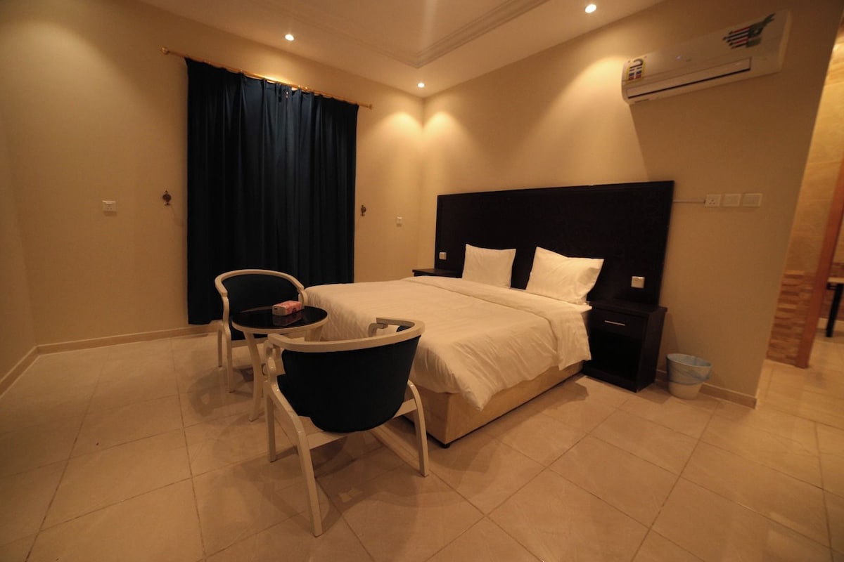 Ein Hotelzimmer mit Bett, Schreibtisch, Stuhl und Nachttisch.