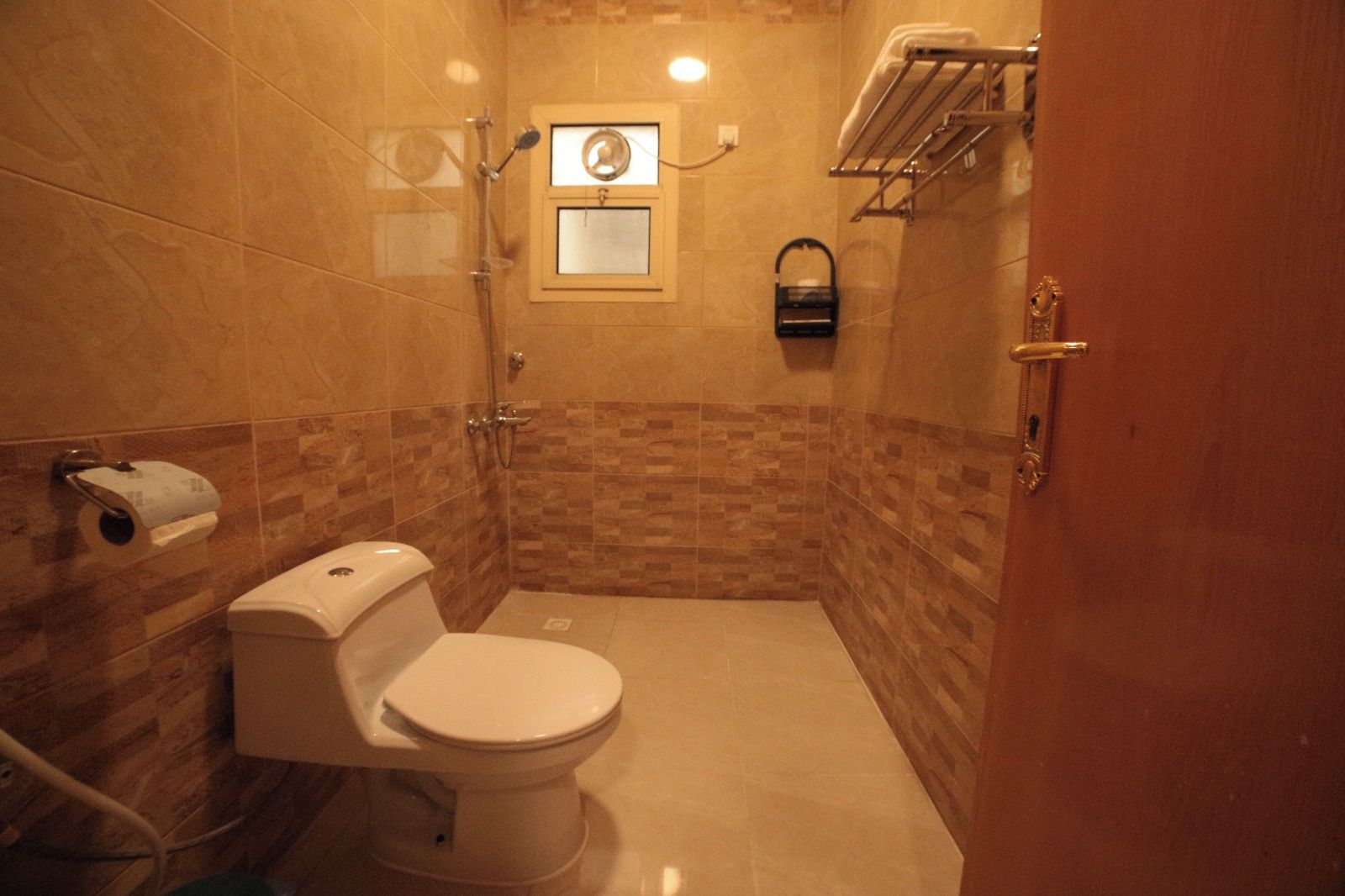 Un bagno con un water, una doccia e un porta asciugamani.