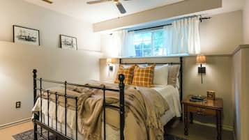 Une chambre à coucher comprenant un lit, une table de chevet, une fenêtre avec des rideaux, un ventilateur de plafond et des lampes fixées au mur.