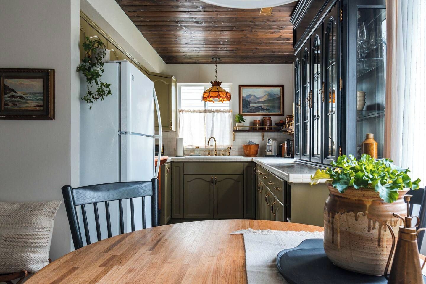 Une cuisine avec un plafond en bois, une table à manger avec des chaises et une grande fenêtre donnant sur un beau paysage.