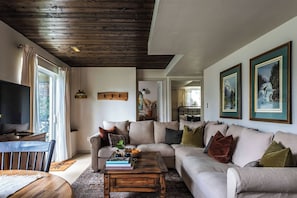A living room with a wooden ceiling, a sofa, a coffee table, and a television.