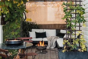 A cozy outdoor seating area with a fire pit, a sofa, and a table.