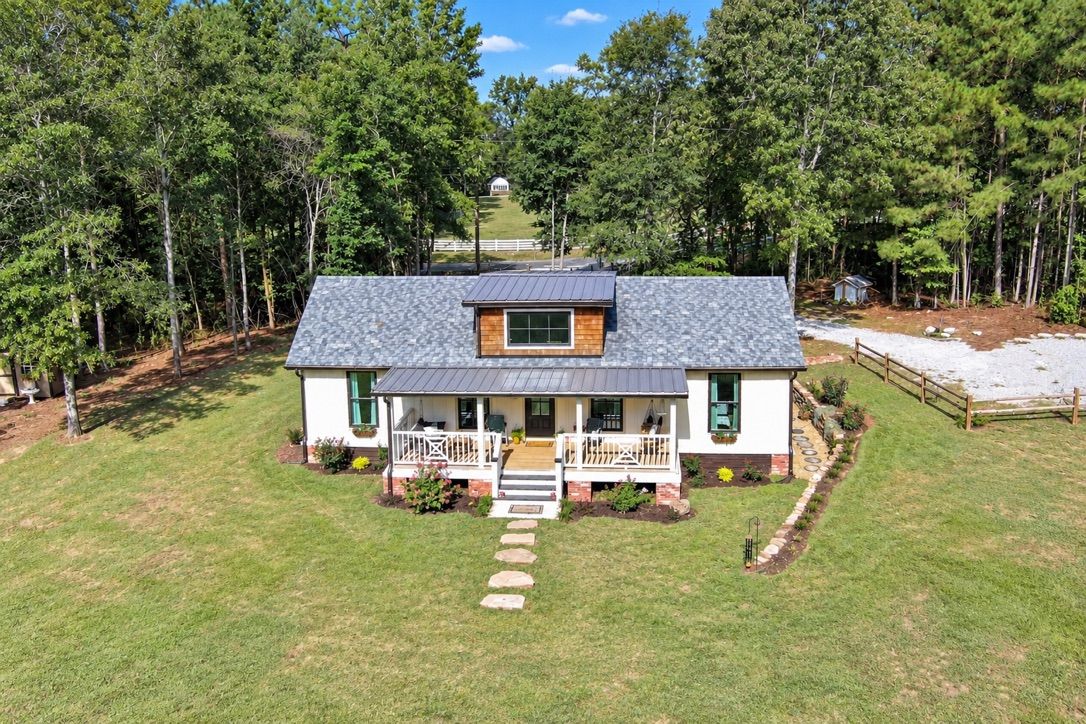 A two-story house with a porch, a stone pathway leading to the entrance, and a fenced yard.
