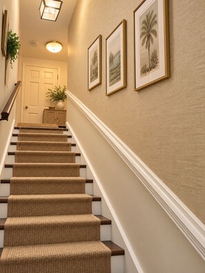 A staircase with a textured carpet, a handrail, and a wall with framed pictures. - Cozy & Stylish 1-Bedroom Retreat Modern Comfort & Private Kitchenette (Tampa)
