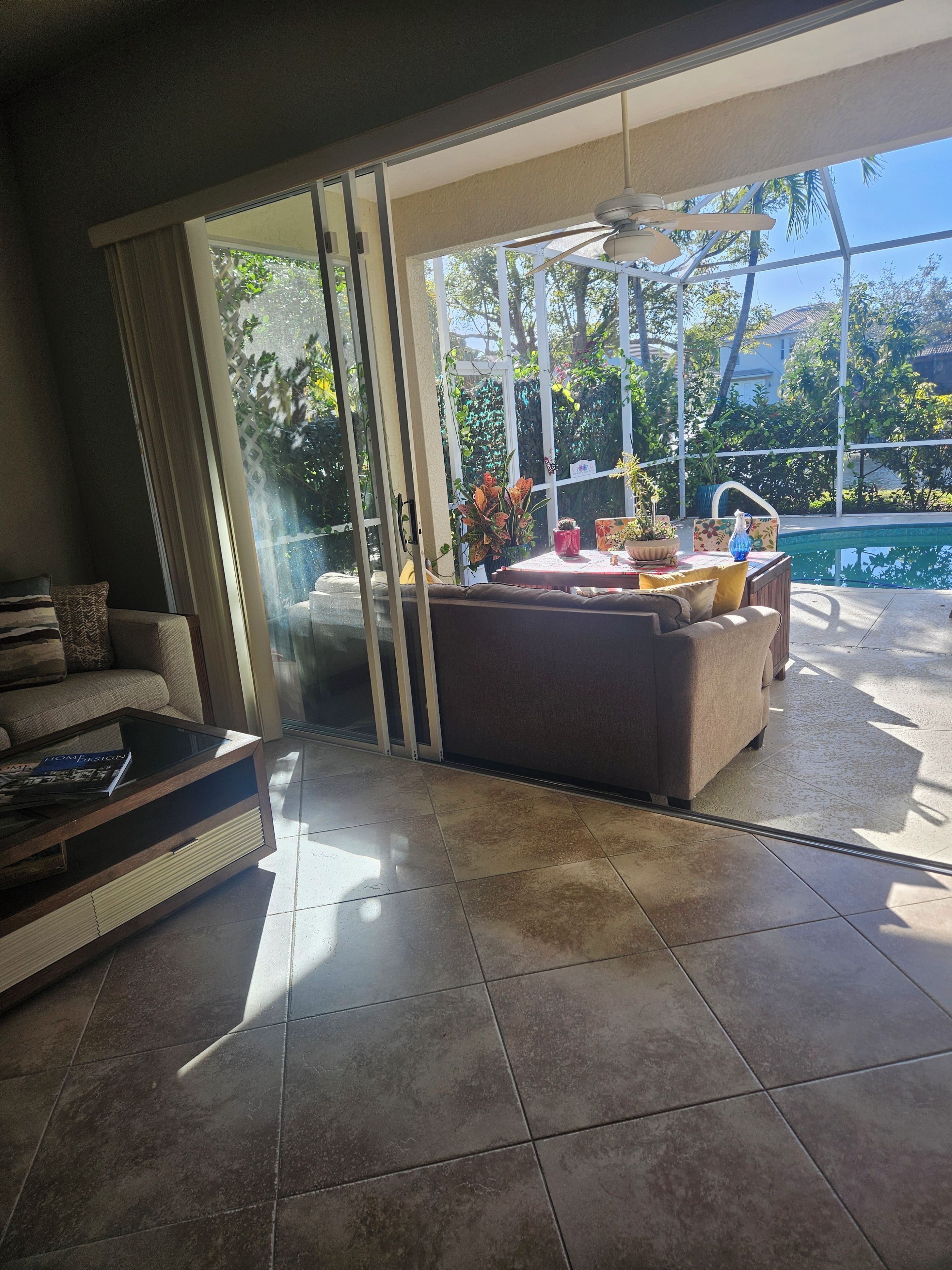 A modern living room with a glass door leading to a pool area, a sofa, and a coffee table.