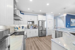 A modern kitchen with white cabinets, stainless steel appliances, and a marble countertop. - NEW! Ocean Views-Steps to Beach-Pool+Spa-Luxury 8BR (Atlantic Beach)