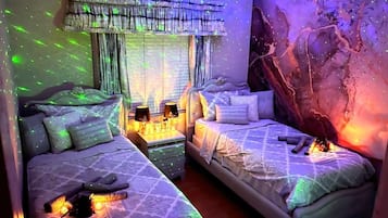Une chambre avec deux lits, une table de chevet avec des lampes et un mur au décor texturé.