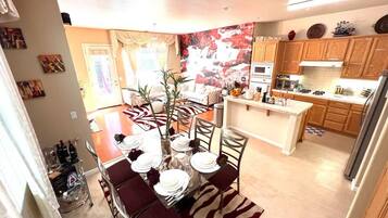 A modern kitchen with wooden cabinets, a central island, and a dining area with a zebra-patterned rug.