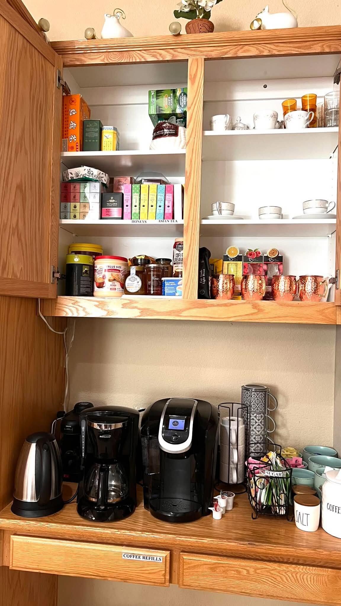 A kitchen with wooden cabinets, a coffee station, and various tea and coffee products.