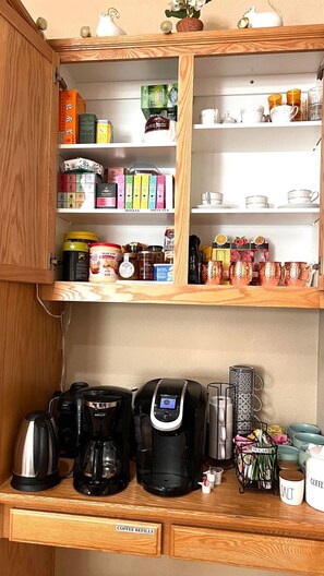Une cuisine dotée de meubles en bois, d’un espace dédié au café et d’une variété de produits à base de thé et de café.