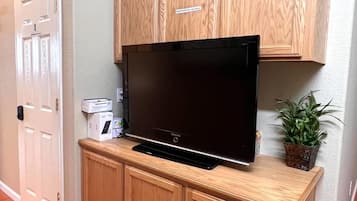 A flat-screen TV on a wooden cabinet with a 'Professional Use Only' sign, a door, and a plant.