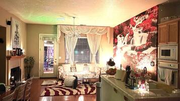 A cozy living room with a fireplace, a sofa, a coffee table, and a dining area with chairs.
