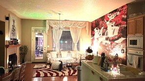 Un salon chaleureux avec une cheminée, un canapé, une table basse et un coin repas avec des chaises.