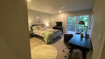 Ein Schlafzimmer mit einem Bett, einem Schreibtisch und Blick ins Freie durch eine Schiebetür.