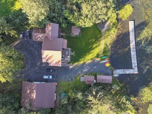 An aerial view of a property with multiple buildings, a paved driveway, and a dock.