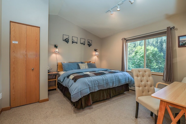 A bedroom with a bed, bedside tables, a chair, a window, and a door. - Take a load off and instantly improve your mood (Seward)
