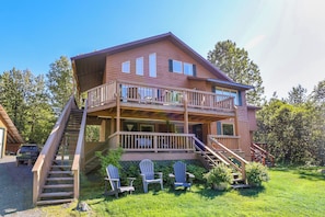 A two-story wooden cabin with a balcony, a staircase, and outdoor seating. - Take a load off and instantly improve your mood (Seward)