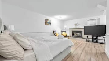 Un dormitorio con cama, televisor, chimenea y un cuadro en la pared.
