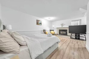 Een slaapkamer met een bed, een televisie, een open haard en een schilderij aan de muur.