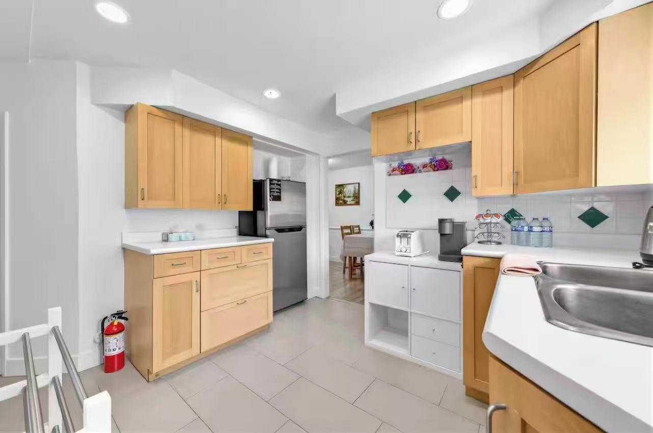 Una cocina moderna con armarios de madera, un lavamanos de acero inoxidable y un refrigerador.
