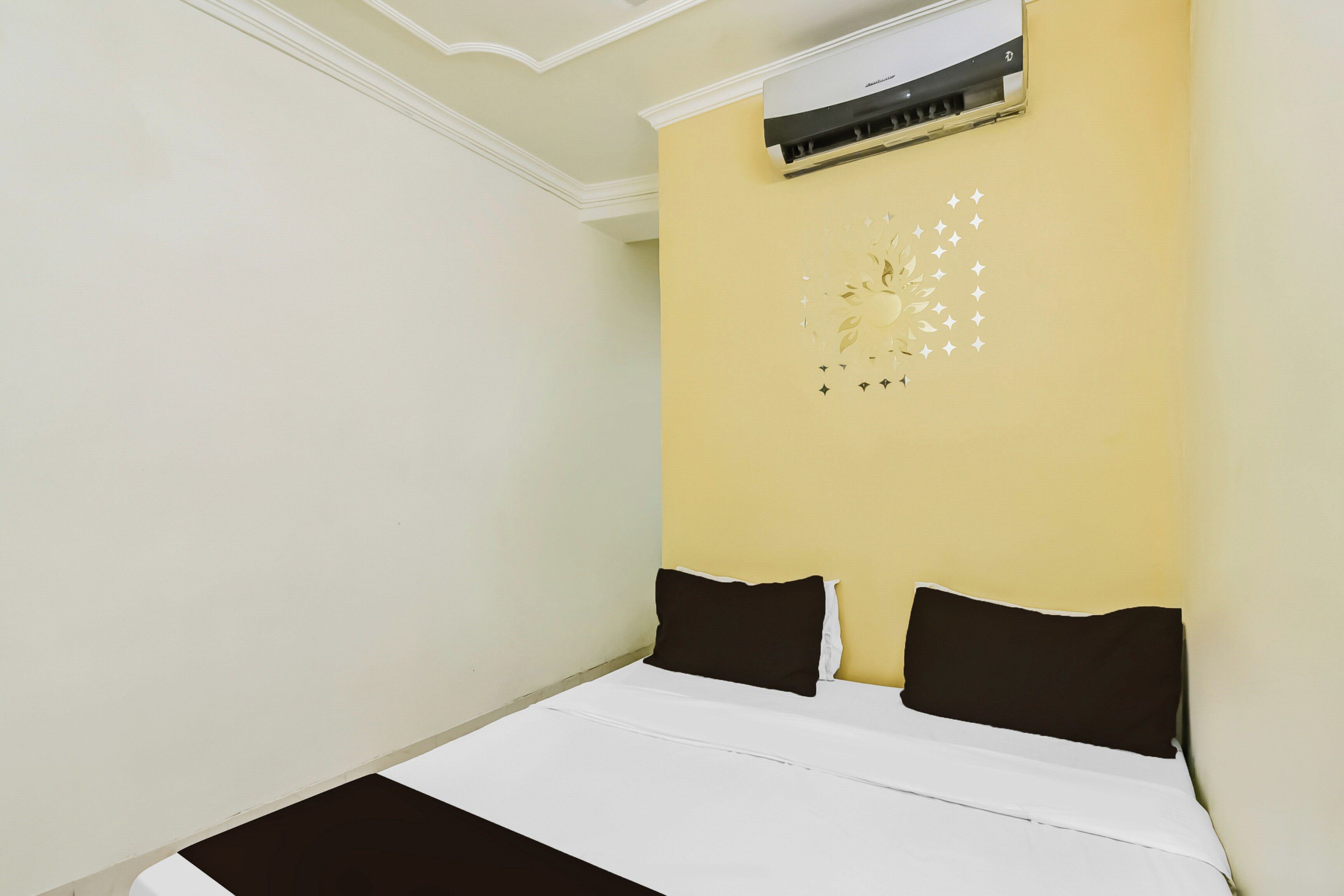 A room with a bed, a wall-mounted air conditioner, and a decorative wall piece.