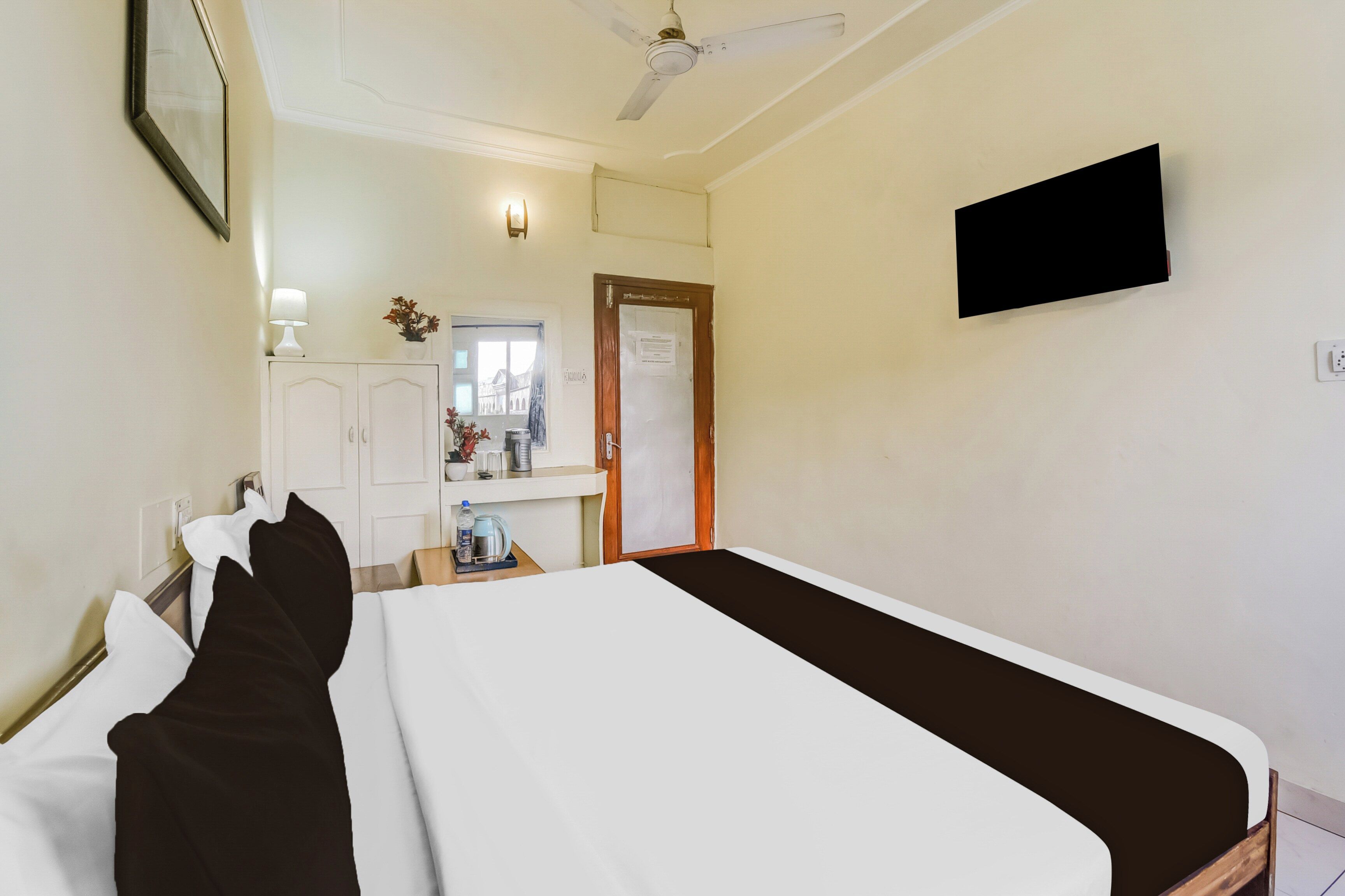 Habitación de hotel con cama, escritorio con lámpara, televisión y puerta que da a un baño.