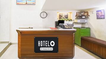 A hotel reception desk with a clock and framed artwork on the wall.