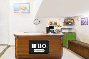 Balcão de recepção de hotel com um relógio e quadros na parede.