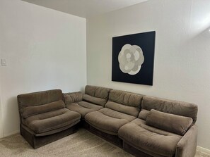 A sectional sofa in a corner of a room with a plain wall and a single piece of abstract art. - Perfect Transition Home (Plano)