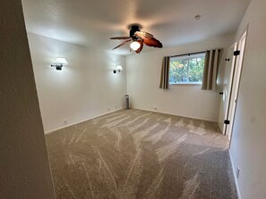 A room with a ceiling fan, two wall-mounted lamps, a radiator, and a window with curtains. - Perfect Transition Home (Plano)
