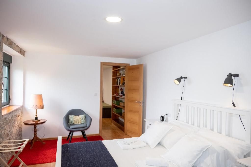 Een slaapkamer met een bed, nachtlampjes, een stoel, een klein tafeltje met een lamp en een kledingkast.