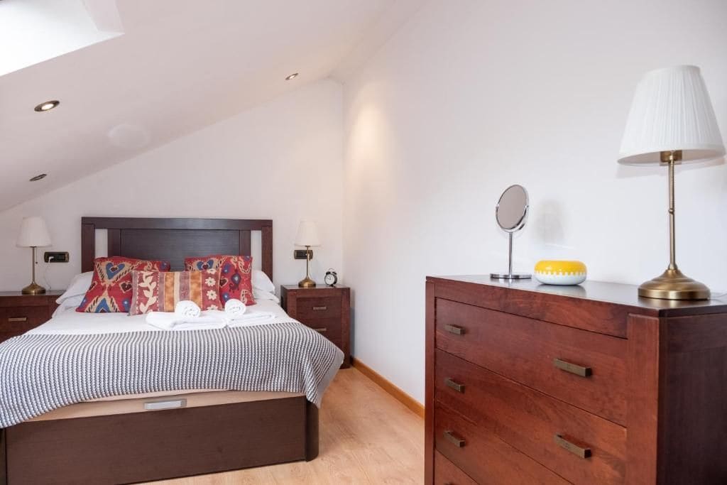Una camera da letto con un letto, comodini, una cassettiera e una lampada.