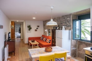 Un espacio habitable compacto con kitchenette, zona de comedor, sofá con cojín de la Union Jack y vistas por una ventana.