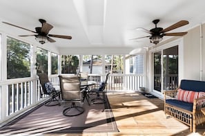 A covered porch with a table and chairs, ceiling fans, and a view of the surrounding area. - Serene 4-bedroom, amazing porches & the BEST that Saint George Island offers (Saint George Island)