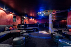 A dimly lit lounge area with seating and a bar counter. - 5BR: Tennis Court, Sauna & Nightclub, 30min SP (Carapicuíba)