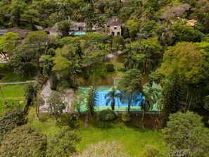 A residential area with a swimming pool surrounded by lush greenery and multiple houses. - 5BR: Tennis Court, Sauna & Nightclub, 30min SP (Carapicuíba)