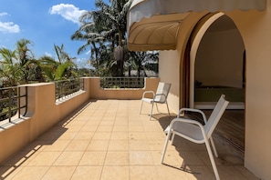 A balcony with two white chairs, a tiled floor, and a view of palm trees. - 5BR: Tennis Court, Sauna & Nightclub, 30min SP (Carapicuíba)