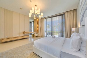 Ein modernes Hotelzimmer mit einem großen Bett, einer eingebauten Sitzbank, einer Sitzecke und Blick ins Freie.
