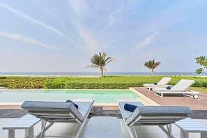 Ein Poolbereich mit Liegestühlen und Blick auf das Meer.