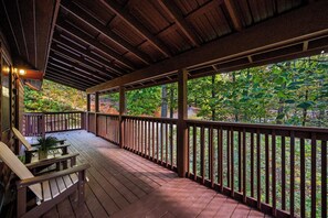 Eine überdachte Terrasse im Freien mit Holzgeländer, einer Bank und einem Tisch mit einer Pflanze.