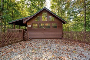 Eine Holzhütte mit überdachter Veranda und befestigter Auffahrt.