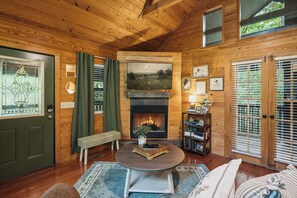 Ein gemütliches Blockhaus-Interieur mit Kamin, Holzwänden, einer Bank und einem Esstisch.